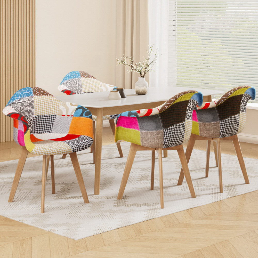 Set of four retro-style dining chairs with colorful velvet patchwork fabric and beech wood legs around a round white table.