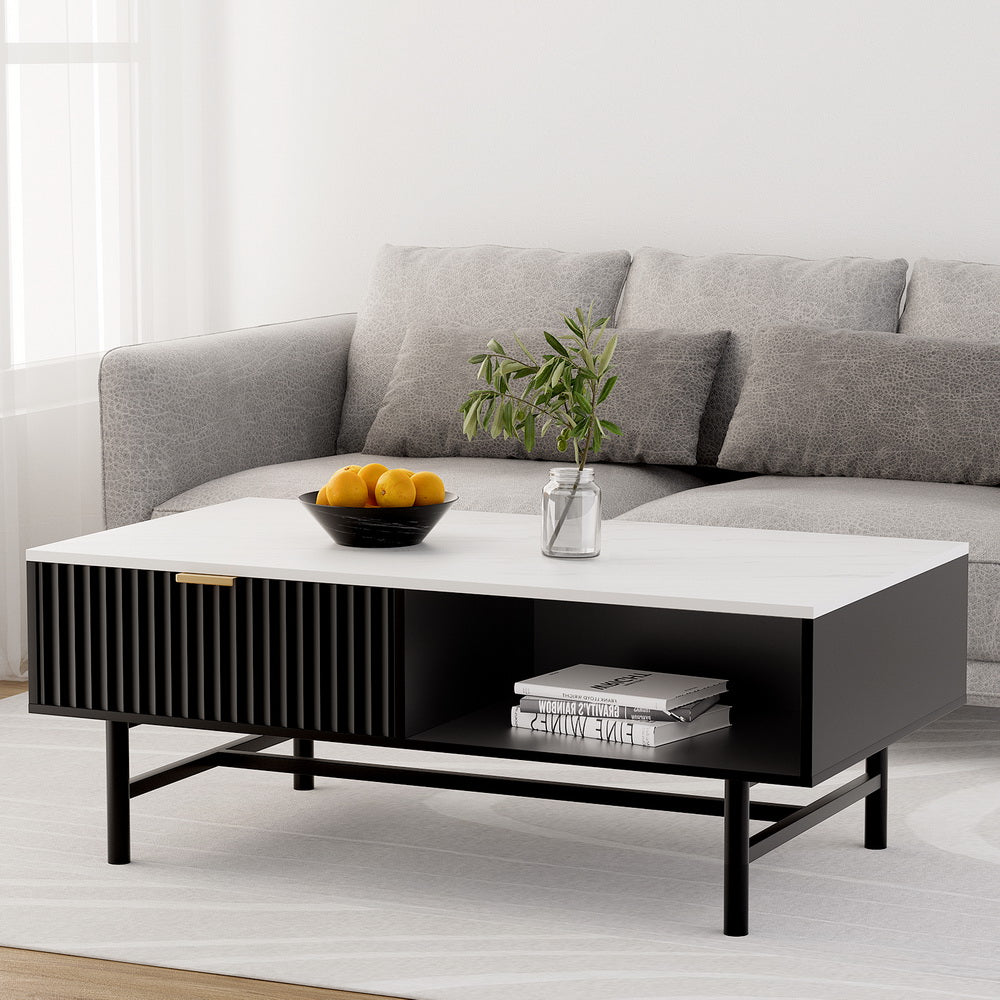Black retro coffee table with drawer and open shelf on black metal legs in a bright living room with gray velvet sofa,.