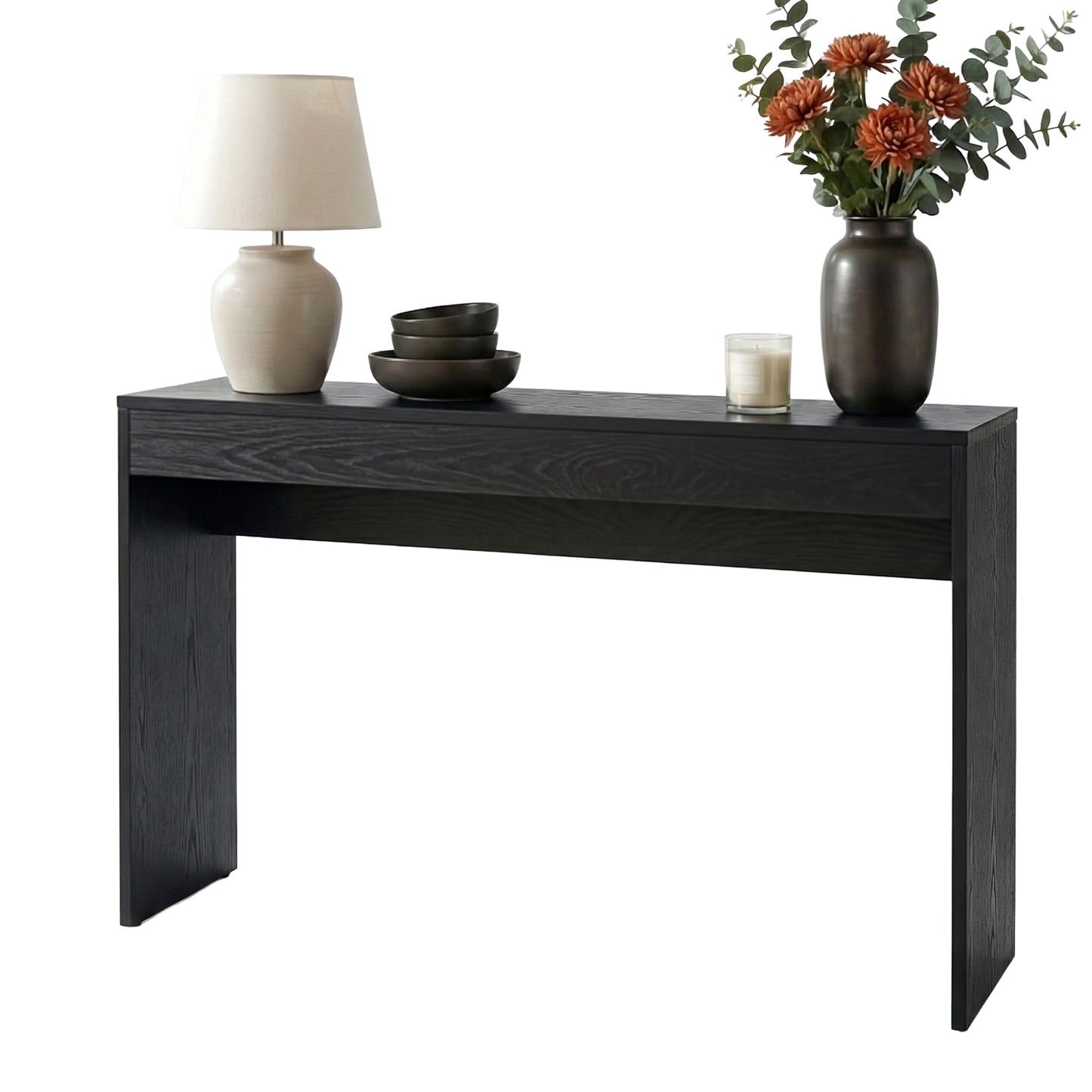 Black console table with decorative items including a lamp, bowls, and a vase with flowers on a white background.