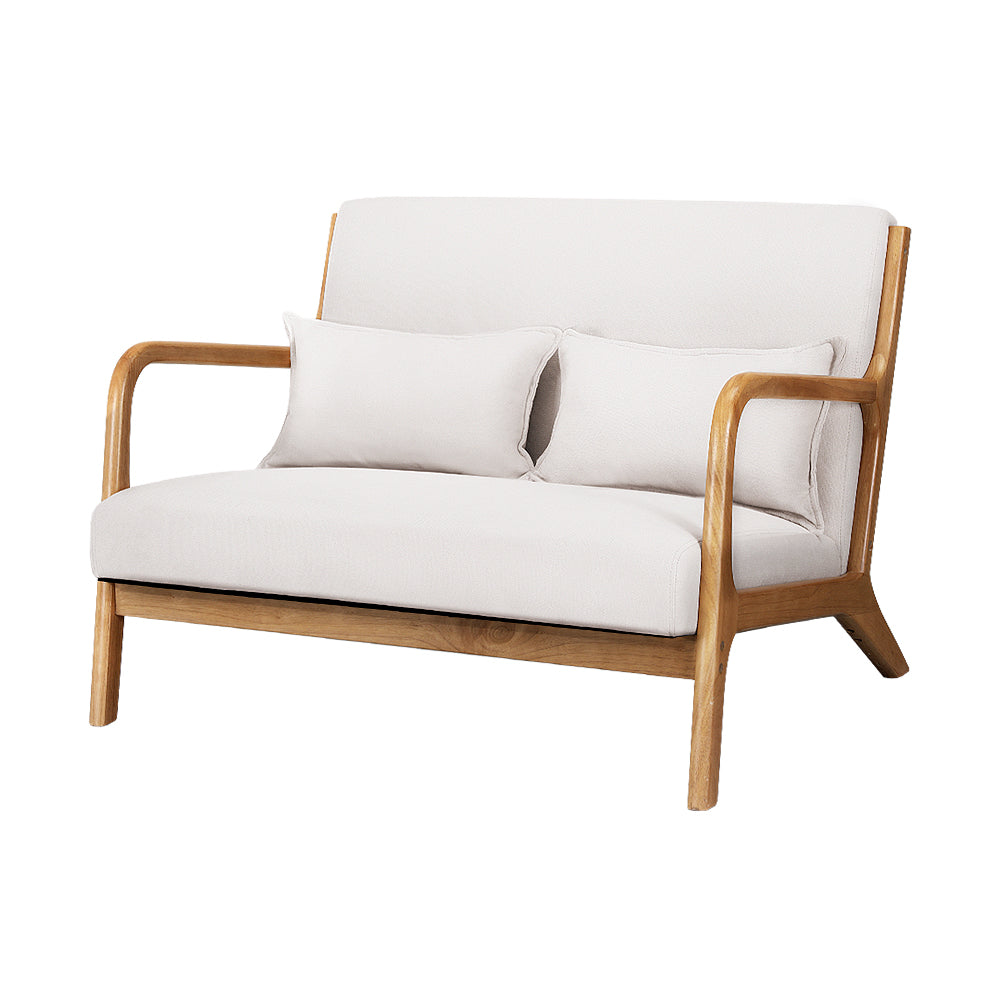 Beige velvet retro armchair with wooden frame and curved armrests, two matching lumbar cushions, minimalist vintage style.