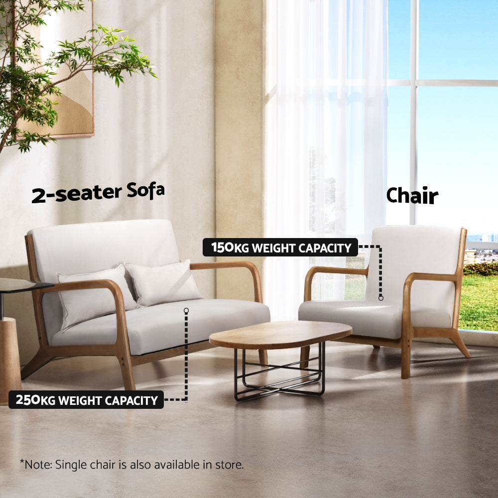 Beige velvet retro armchair with wooden frame in bright living room next to matching 2-seater sofa and round wooden coffee.