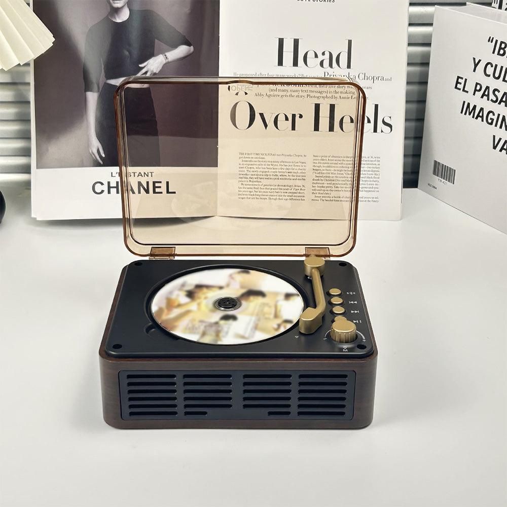 Vintage-style record player with a CD on a white surface, with books in the background.