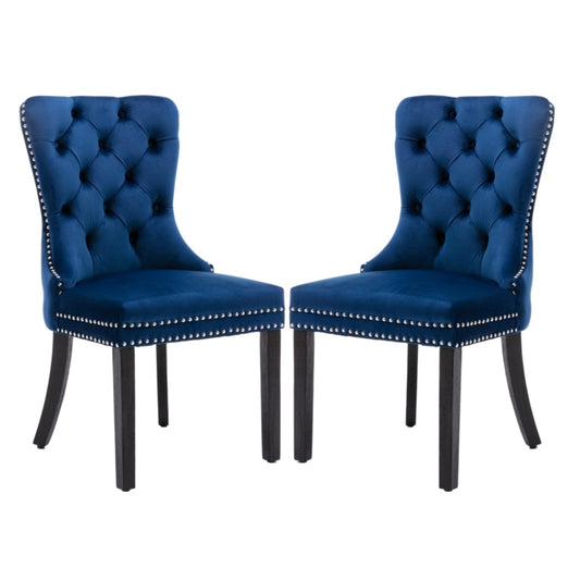 Pair of blue velvet tufted dining chairs with wingback design, studded trim, and dark solid wood legs, showcasing a vintage.