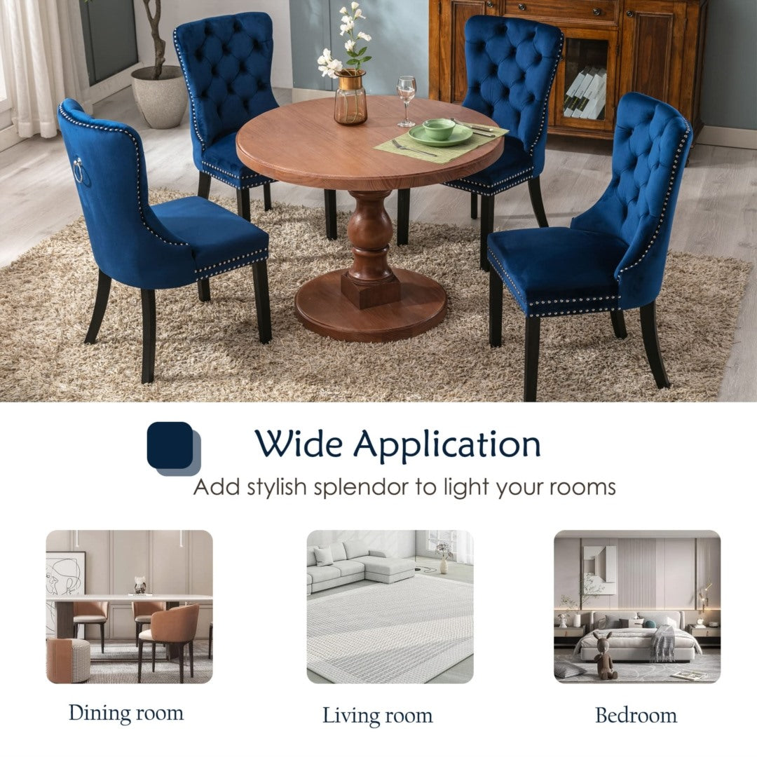 Set of four blue velvet tufted wingback dining chairs with stud trim and dark solid wood legs around a round wooden pedestal .