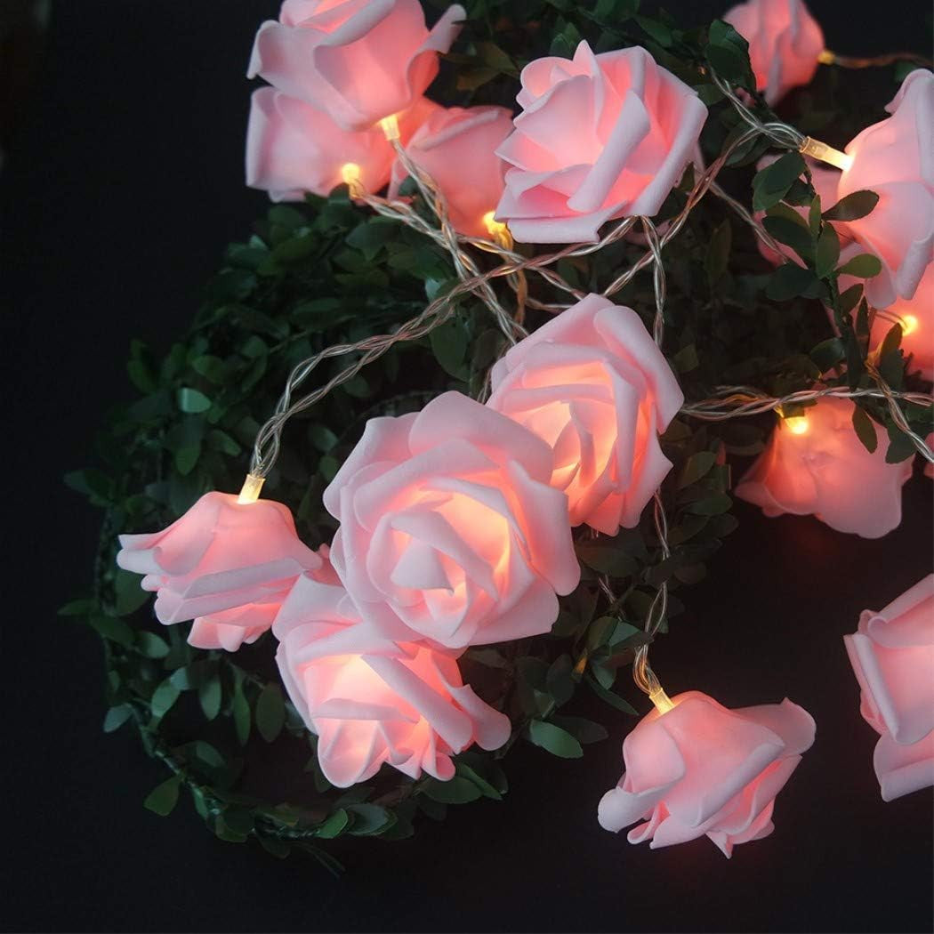 Soft pink velvet 3D rose fairy lights glowing warmly on a dark green leafy backdrop, creating a vintage, romantic ambiance.