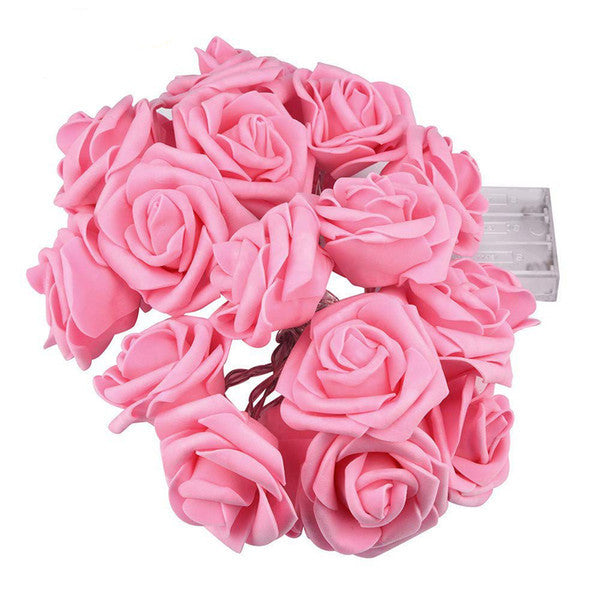 Close-up of pink velvet 3D rose fairy lights on a brown wire with a clear battery pack, vintage-inspired home decor for.