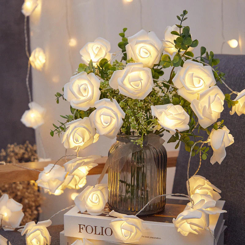 50 white rose 3D fairy lights with soft velvet petals, wrapped around a vintage glass vase filled with greenery, styled on.
