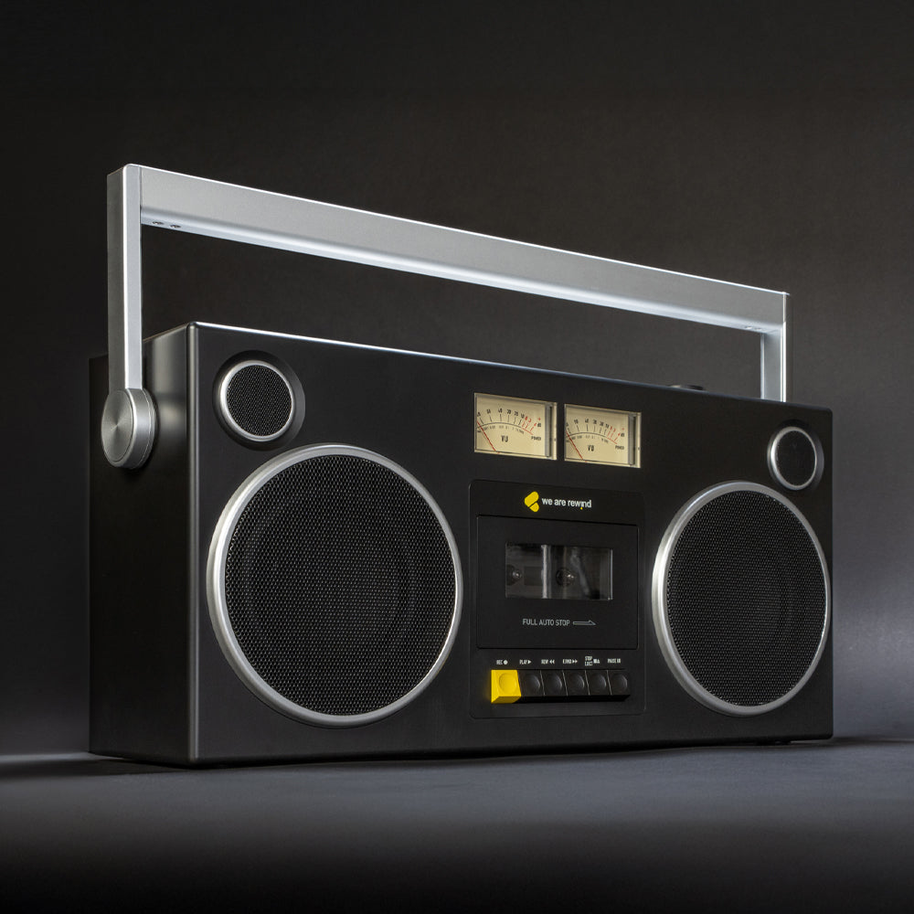 Black retro Getto Blaster cassette player with silver handle, vintage dials, and dual speakers on a dark surface, showcasing .